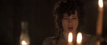 Movie still from “The Claim” (2000), directed by Michael Winterbottom – A woman is holding a candle in her mouth; Close Up shot, Low angle