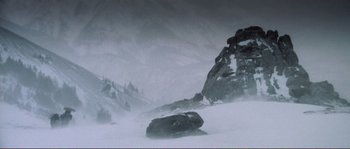 Movie still from “The Claim” (2000), directed by Michael Winterbottom – A snowy mountain with a rock formation in the background; Extreme Wide shot, Low angle