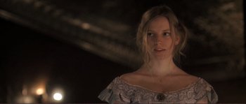Movie still from “The Claim” (2000), directed by Michael Winterbottom – A young woman in a dress is looking at the camera; Close Up shot, Over the shoulder angle