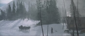 Movie still from “The Claim” (2000), directed by Michael Winterbottom – A man riding a sled down a snow covered slope; Extreme Wide shot, High angle