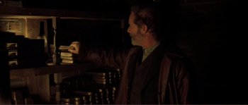 Movie still from “The Claim” (2000), directed by Michael Winterbottom – A man standing in front of a stack of cans; Medium shot, Low angle