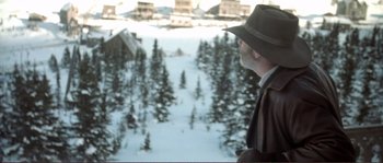 Movie still from “The Claim” (2000), directed by Michael Winterbottom – A man wearing a hat looking out over a snow covered forest; Medium shot, High angle