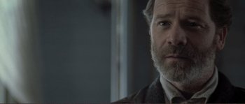 Movie still from “The Claim” (2000), directed by Michael Winterbottom – A person wearing a suit and tie; Close Up shot, Over the shoulder angle