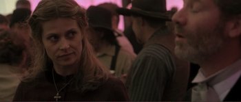 Movie still from “The Claim” (2000), directed by Michael Winterbottom – A woman standing in front of a group of people; Close Up shot, Over the shoulder angle