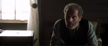 Movie still from “The Claim” (2000), directed by Michael Winterbottom – An older man sitting in front of a computer monitor; Close Up shot, Over the shoulder angle