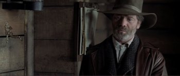 Movie still from “The Claim” (2000), directed by Michael Winterbottom – A man wearing a hat and a suit; Close Up shot, Low angle