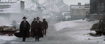 Movie still from “The Claim” (2000), directed by Michael Winterbottom – A group of men walking down a snow covered road; Wide shot, Low angle