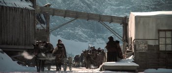 Movie still from “The Claim” (2000), directed by Michael Winterbottom – A group of people riding on the back of a horse drawn carriage; Wide shot, High angle