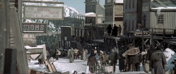 Movie still from “The Claim” (2000), directed by Michael Winterbottom – A group of people standing on top of a snow covered slope; Extreme Wide shot, High angle
