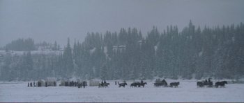 Movie still from “The Claim” (2000), directed by Michael Winterbottom – A group of people riding horses in a snowy field; Extreme Wide shot, High angle
