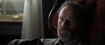 Movie still from “The Claim” (2000), directed by Michael Winterbottom – An older man sitting in a chair with his eyes wide open; Close Up shot, High angle
