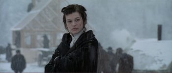 Movie still from “The Claim” (2000), directed by Michael Winterbottom – A woman in a black coat standing in the rain; Medium shot, Low angle