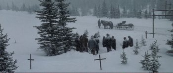 Movie still from “The Claim” (2000), directed by Michael Winterbottom – A group of people walking in the snow near a cross; Wide shot, High angle
