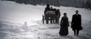 Movie still from “The Claim” (2000), directed by Michael Winterbottom – A group of people riding in a horse drawn carriage through a snow covered field; Wide shot, High angle