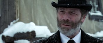 Movie still from “The Claim” (2000), directed by Michael Winterbottom – An older man wearing a black hat and a white tie; Close Up shot, Over the shoulder angle