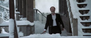 Movie still from “The Claim” (2000), directed by Michael Winterbottom – A man in a suit and tie holding a sword; Medium shot, Low angle