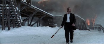 Movie still from “The Claim” (2000), directed by Michael Winterbottom – A man in a suit and tie holding an object in his hand; Medium shot, Low angle