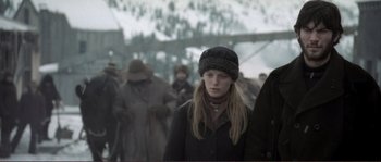 Movie still from “The Claim” (2000), directed by Michael Winterbottom – A woman wearing a winter hat and a black coat; Medium shot, Low angle