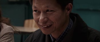 Movie still from “The Class” (2008), directed by Laurent Cantet – A person wearing a suit and smiling; Close Up shot, Over the shoulder angle