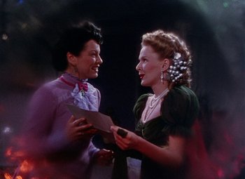 Movie still from “The Climax” (1944), directed by George Waggner – Two women are talking to each other while holding papers; Medium shot, Low angle