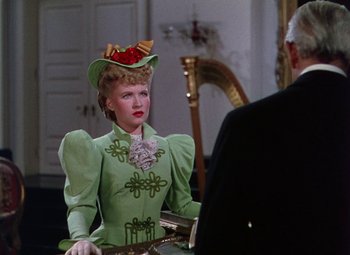 Movie still from “The Climax” (1944), directed by George Waggner – A woman wearing a green dress and a hat; Medium shot, Over the shoulder angle
