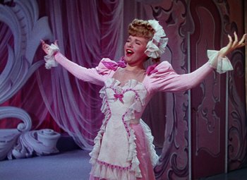 Movie still from “The Climax” (1944), directed by George Waggner – A woman dressed as a maid in a pink dress; Medium shot, Low angle