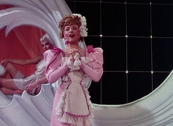 Movie still from “The Climax” (1944), directed by George Waggner – A woman in a pink dress standing in front of a mirror; Medium shot, Low angle
