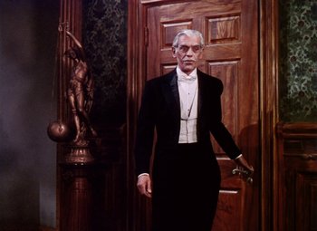 Movie still from “The Climax” (1944), directed by George Waggner – A man in a tuxedo standing in front of a wooden door; Medium shot, Low angle