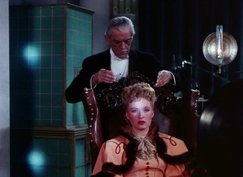 Movie still from “The Climax” (1944), directed by George Waggner – An older man is cutting a woman's hair; Medium shot, Over the shoulder angle