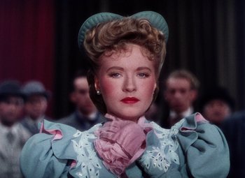 Movie still from “The Climax” (1944), directed by George Waggner – A woman in a blue and white dress with a pink bow around her neck; Close Up shot, Low angle
