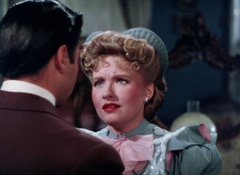Movie still from “The Climax” (1944), directed by George Waggner – A woman in a pink hat and a man in a blue suit; Close Up shot, Over the shoulder angle