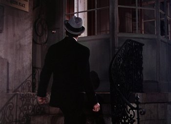 Movie still from “The Climax” (1944), directed by George Waggner – A man in a suit and a hat walking down a street; Wide shot, High angle