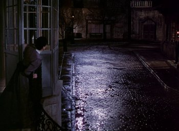 Movie still from “The Climax” (1944), directed by George Waggner – A person leaning against a wall on a street; Wide shot, High angle