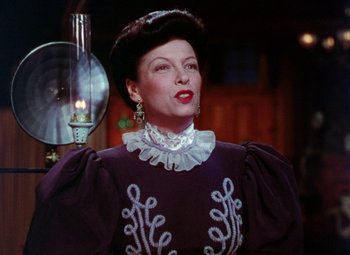 Movie still from “The Climax” (1944), directed by George Waggner – A woman in a purple dress and a black hat; Close Up shot, Low angle
