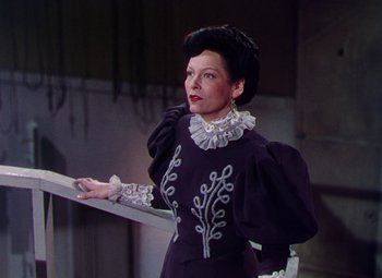 Movie still from “The Climax” (1944), directed by George Waggner – A woman wearing a black dress and a white hat; Medium shot, Low angle