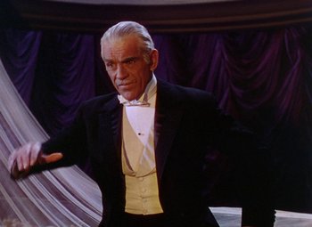Movie still from “The Climax” (1944), directed by George Waggner – An older man in a tuxedo is standing in front of a purple curtain; Medium shot, Low angle