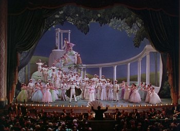 Movie still from “The Climax” (1944), directed by George Waggner – A large group of people on a stage in front of an audience; Extreme Wide shot, High angle
