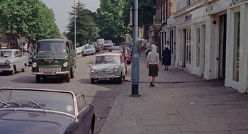Movie still from “The Collector” (1965), directed by William Wyler – An older woman walking down the street with a car; Wide shot, High angle