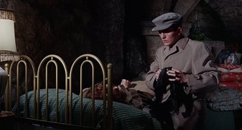 Movie still from “The Collector” (1965), directed by William Wyler – A man sitting on a bed looking at a teddy bear; Medium shot, High angle