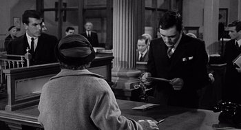 Movie still from “The Collector” (1965), directed by William Wyler – An old photo of two men in a courtroom; Medium shot, Over the shoulder angle