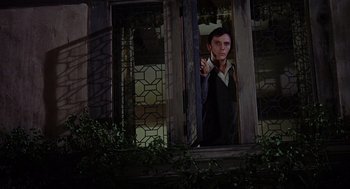 Movie still from “The Collector” (1965), directed by William Wyler – A man standing in a doorway pointing to the side; Medium shot, Low angle