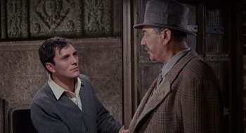 Movie still from “The Collector” (1965), directed by William Wyler – A man in a suit and a man in a hat shake hands; Medium shot, Over the shoulder angle
