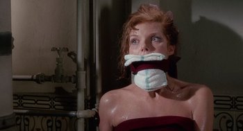 Movie still from “The Collector” (1965), directed by William Wyler – A woman in a red dress is tied to a pipe; Close Up shot, Low angle