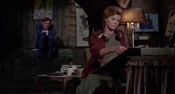 Movie still from “The Collector” (1965), directed by William Wyler – A woman sitting on a chair in front of a lamp; Wide shot, High angle