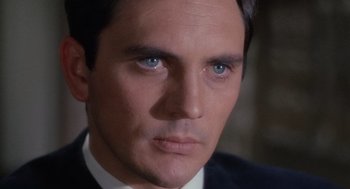 Movie still from “The Collector” (1965), directed by William Wyler – A man with blue eyes wearing a suit; Close Up shot, High angle