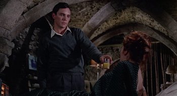 Movie still from “The Collector” (1965), directed by William Wyler – A man is pouring a drink into a woman's hand; Medium shot, Over the shoulder angle