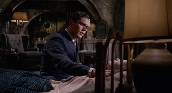 Movie still from “The Collector” (1965), directed by William Wyler – A man sitting on a bed next to a woman; Medium shot, High angle