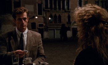 Movie still from “The Comfort of Strangers” (1990), directed by Paul Schrader – A man and a woman are sitting at a table; Medium shot, Over the shoulder angle