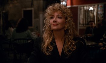 Movie still from “The Comfort of Strangers” (1990), directed by Paul Schrader – A woman with long blonde curly hair sitting in a room; Close Up shot, Over the shoulder angle