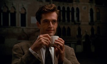 Movie still from “The Comfort of Strangers” (1990), directed by Paul Schrader – A man in a suit holding a coffee cup; Medium shot, Low angle